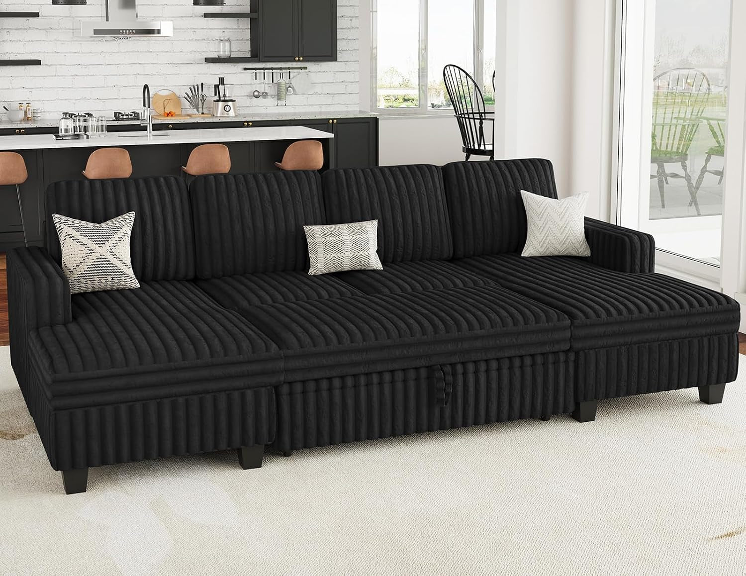Front-facing black corduroy sectional shown flattened into a wide sleeper across the room