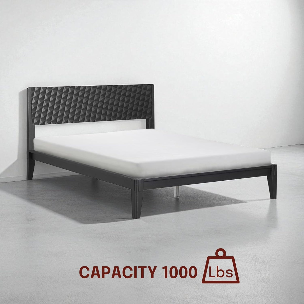 Three-quarter view of a black wood bed in an empty room with a mattress on the slatted frame