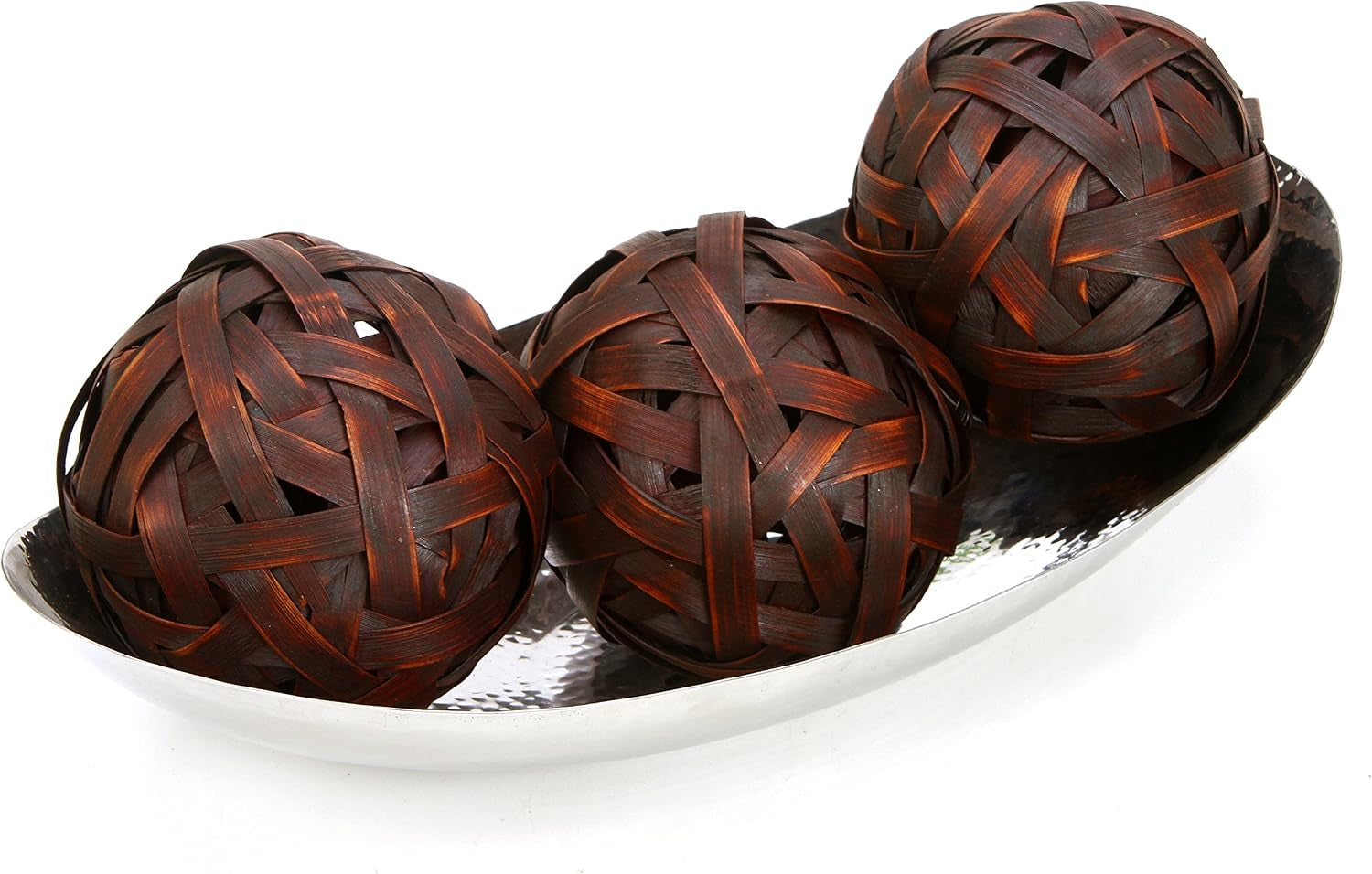 Hammered stainless steel oval bowl filled with three brown woven decorative balls on white background