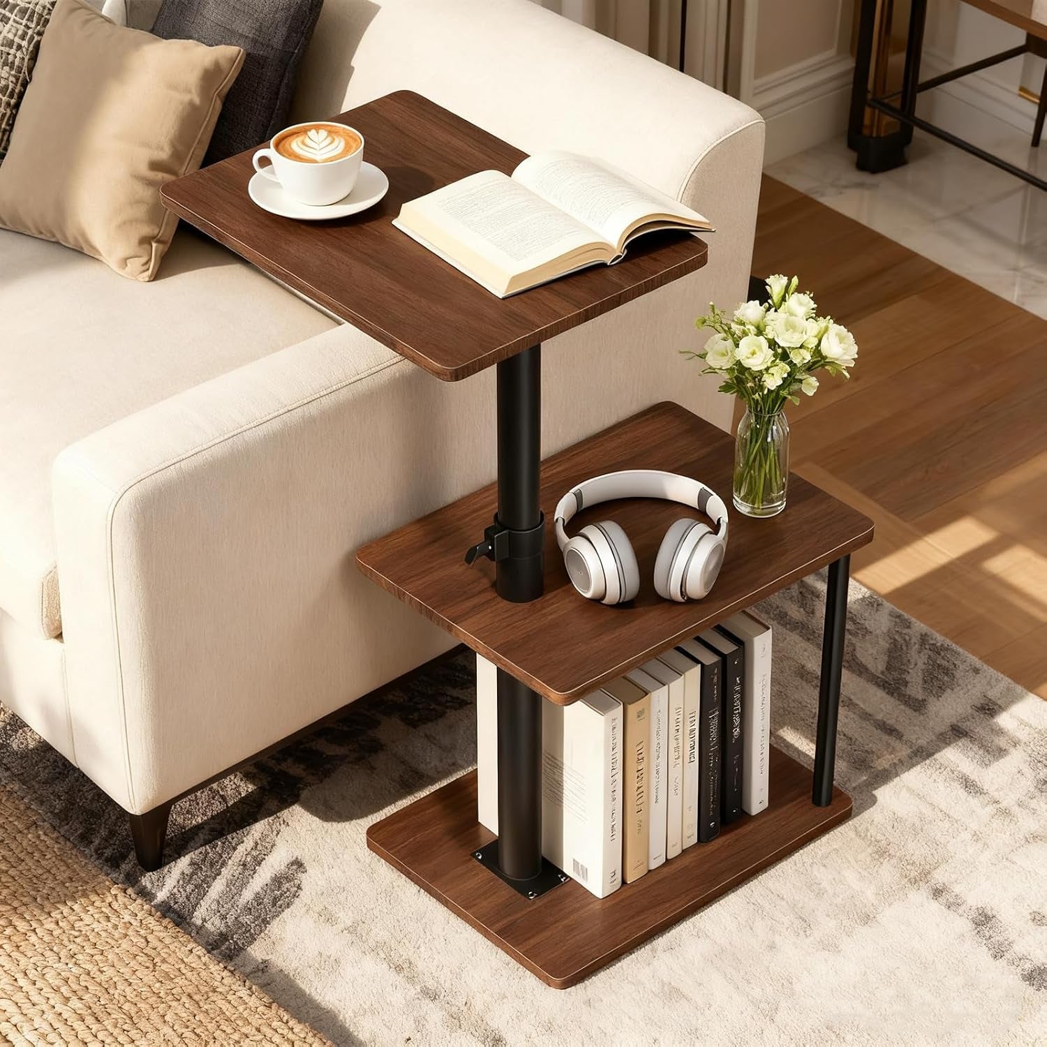 Warm brown three-tier swivel side table beside a cream sofa with coffee cup and headphones on top.