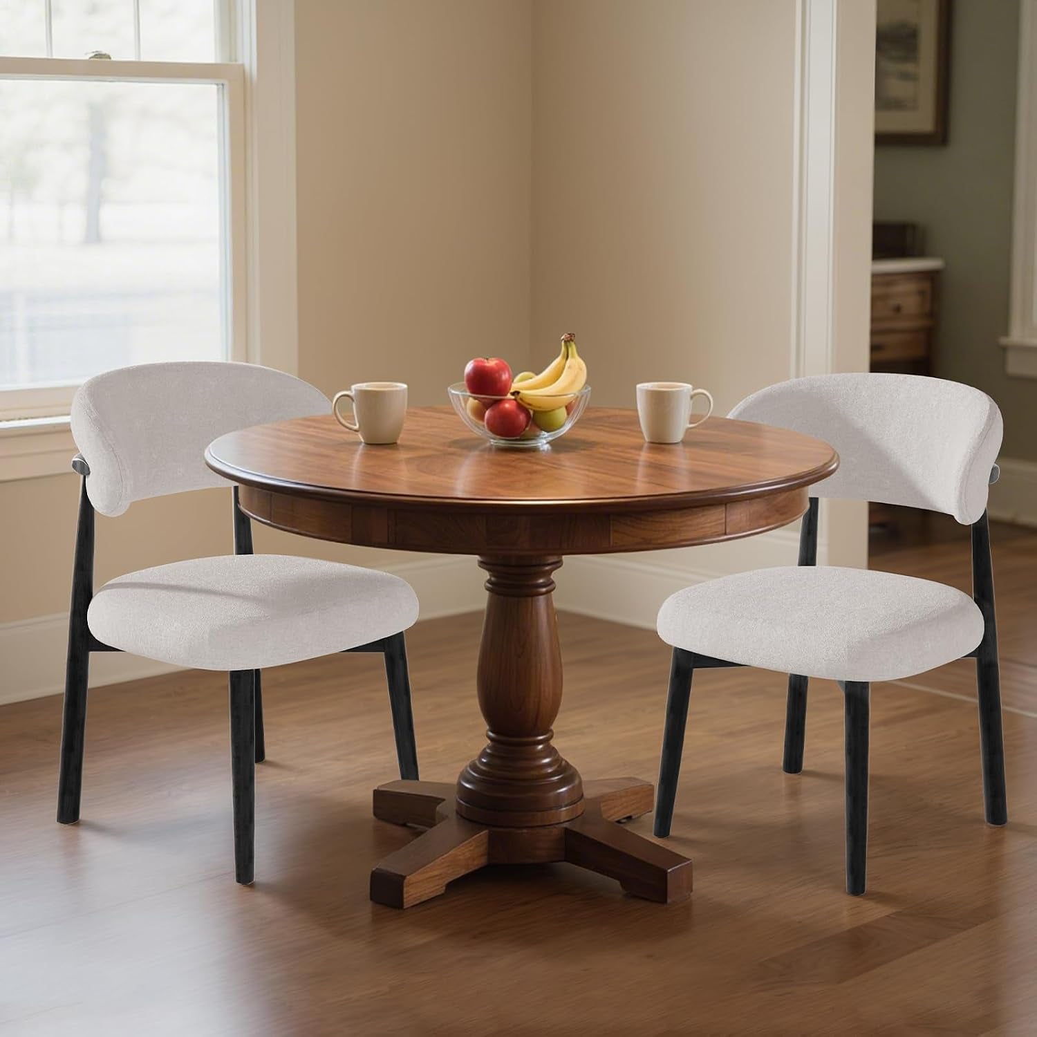 Two pale gray curved-back dining chairs with black frames flank a round table.