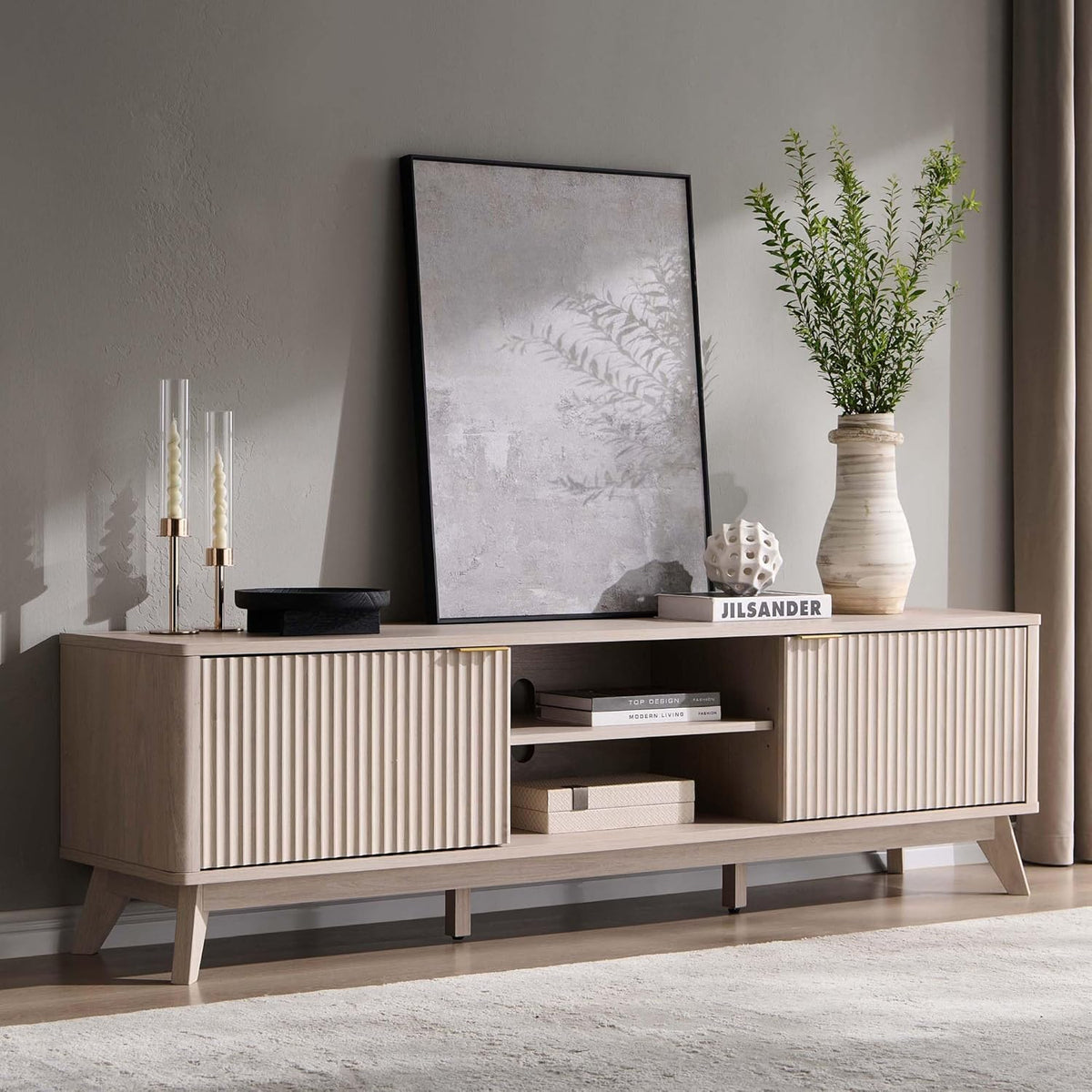 Light wood TV stand styled in a neutral living room with mirror and vase on top.