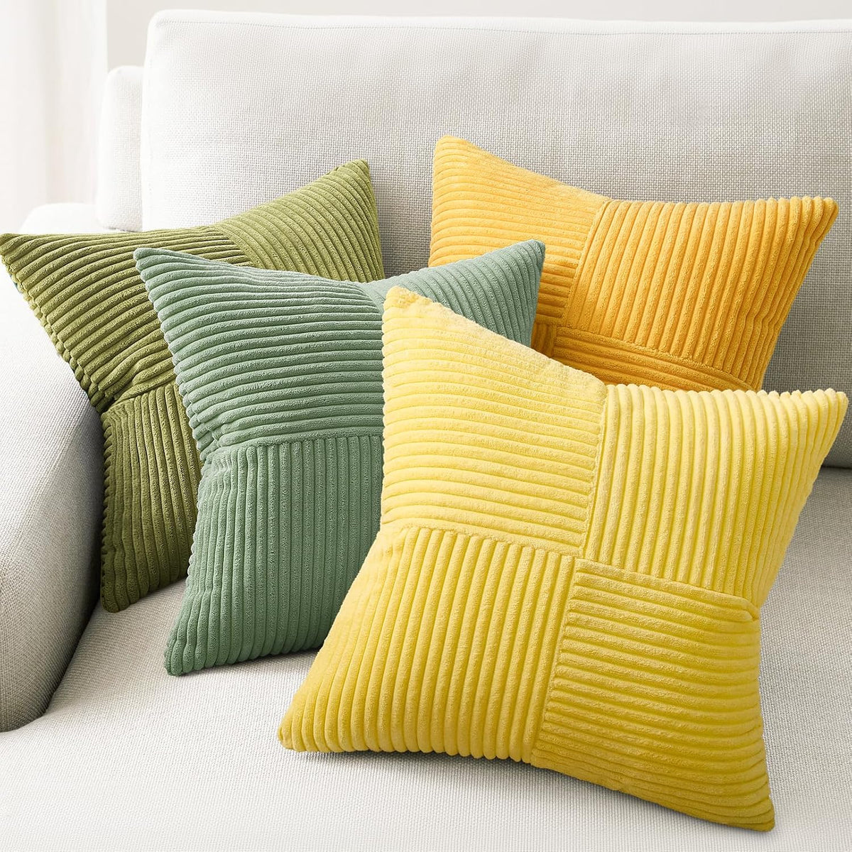 Yellow and green corduroy patchwork pillow covers arranged in a layered display on a sofa.