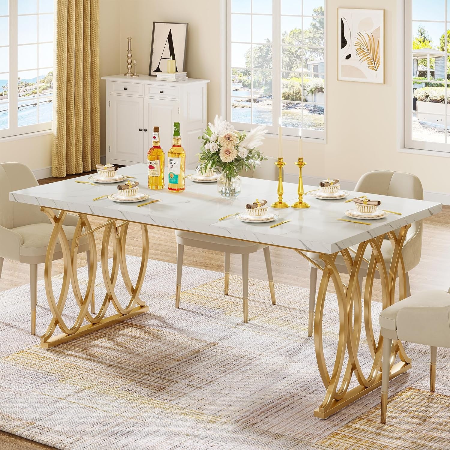 63" white faux marble dining table with gold-bronze circular-motif legs staged with place settings near windows