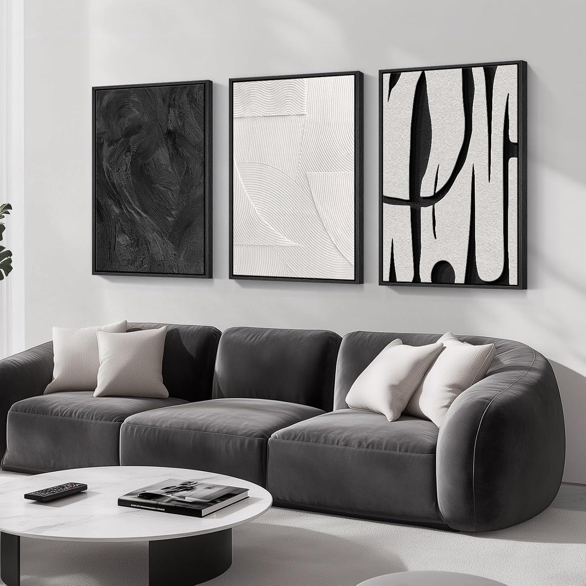 Three vertical black-framed abstract panels in black, white and textured patterns above a dark gray curved sofa.