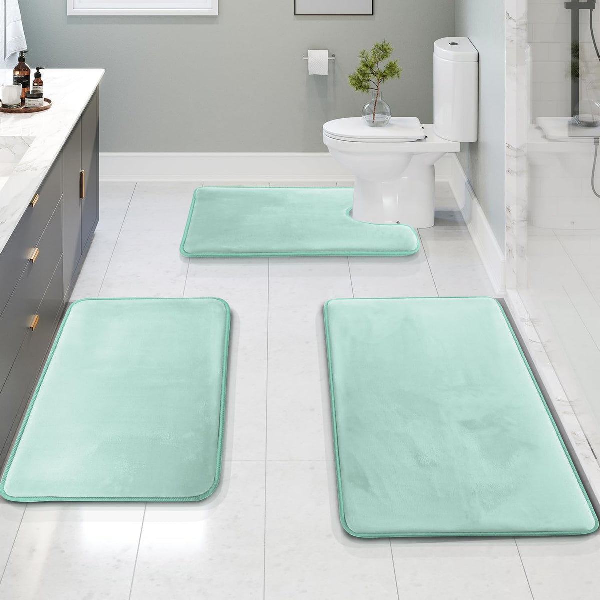 Installed three-piece mint bath mat set: U-shaped toilet mat and two rectangular mats on a tiled bathroom floor.