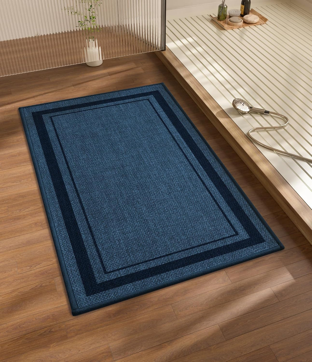 Blue rectangular bath rug on wood floor next to a raised shower platform and handheld showerhead