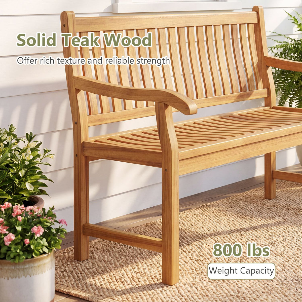 Honey-toned wooden garden bench with slatted seat and back on a woven rug beside potted flowers.