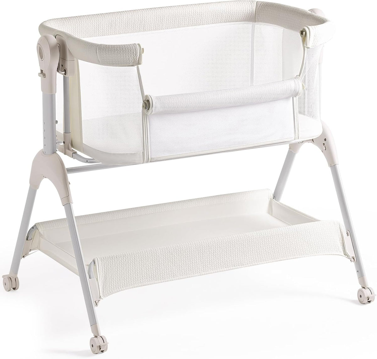 Off-white bedside bassinet with mesh sides and a textured off-white storage shelf on a wheeled frame.