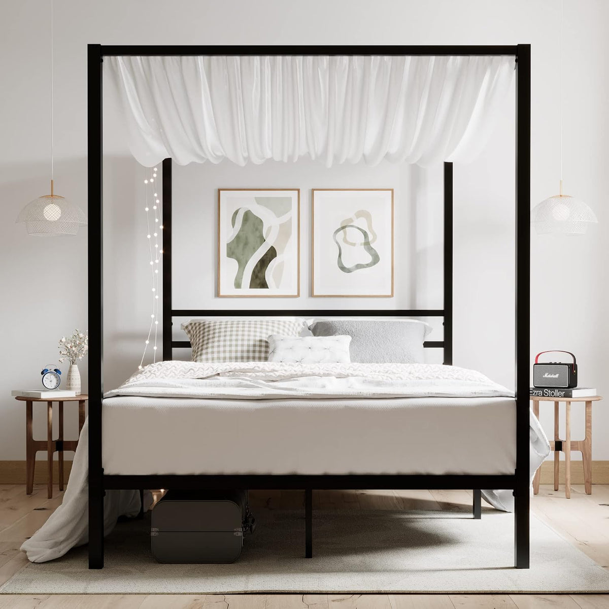 Front-facing view of a black metal canopy bed styled in a bright bedroom with bedside tables and hanging lamps