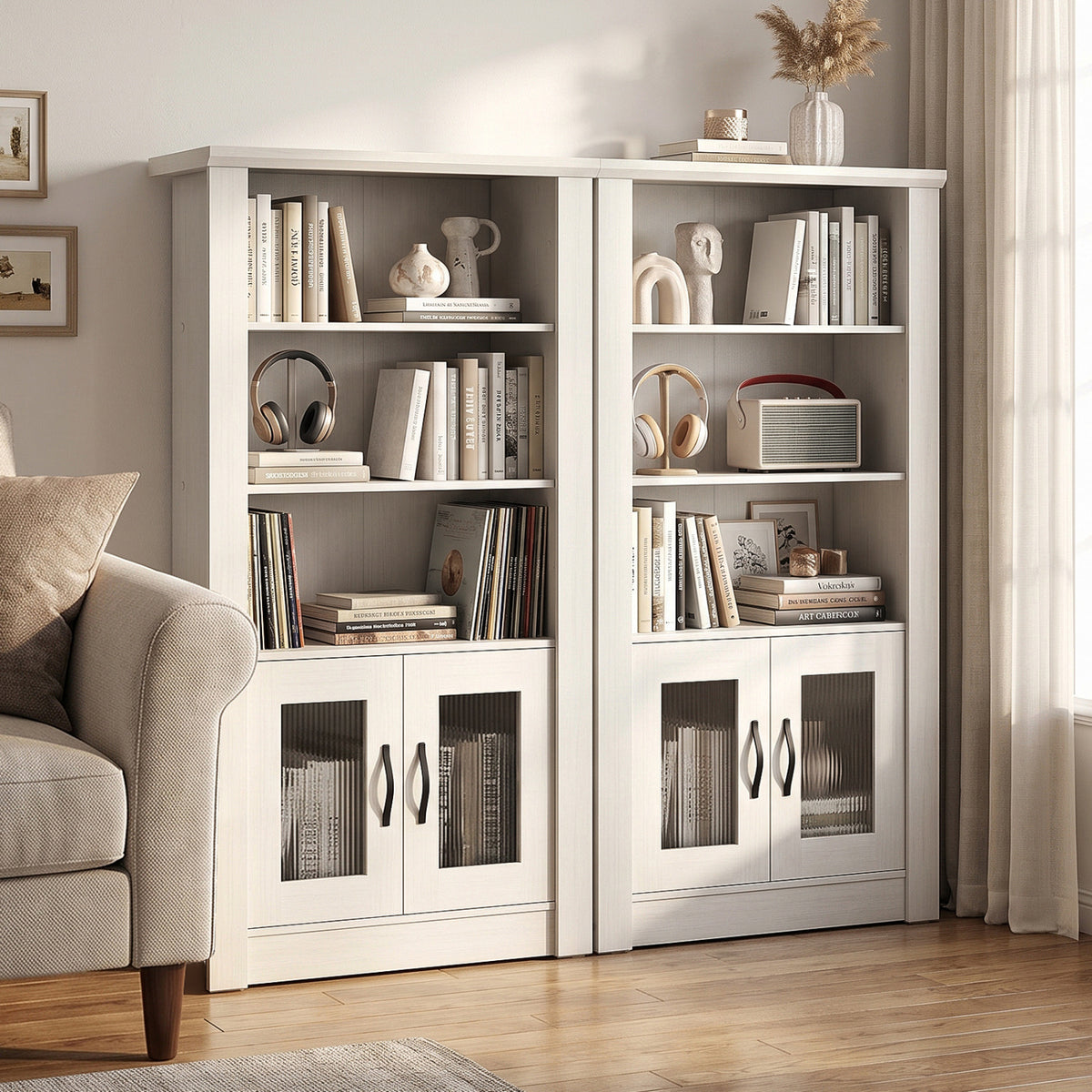Two white bookcases filled with books and decor stand beside a beige armchair and curtains.