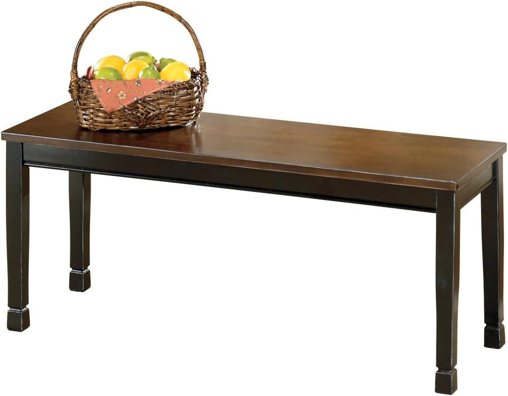 Bench with a warm brown top and darker painted base, basket of fruit placed on top.