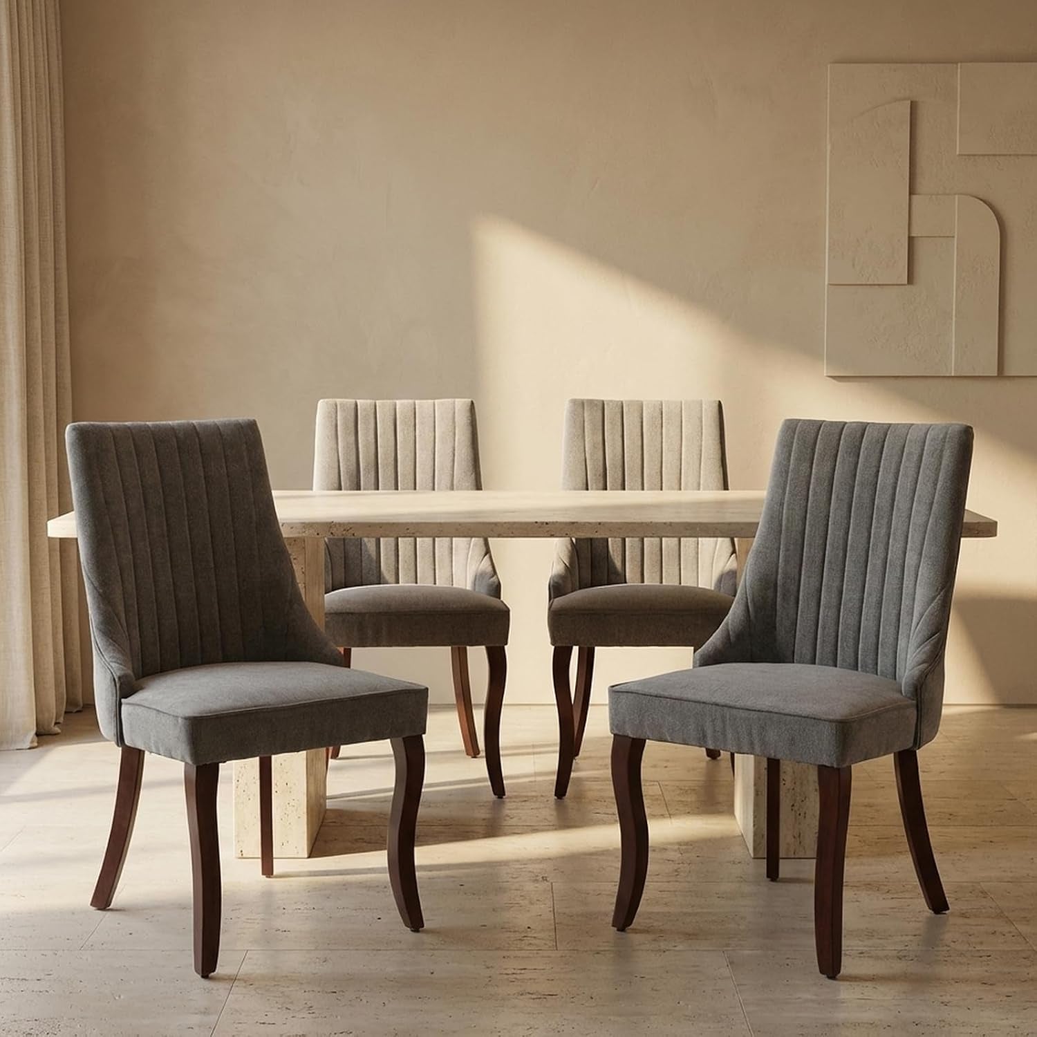 Four gray upholstered high-back dining chairs around a rectangular stone table in soft natural light