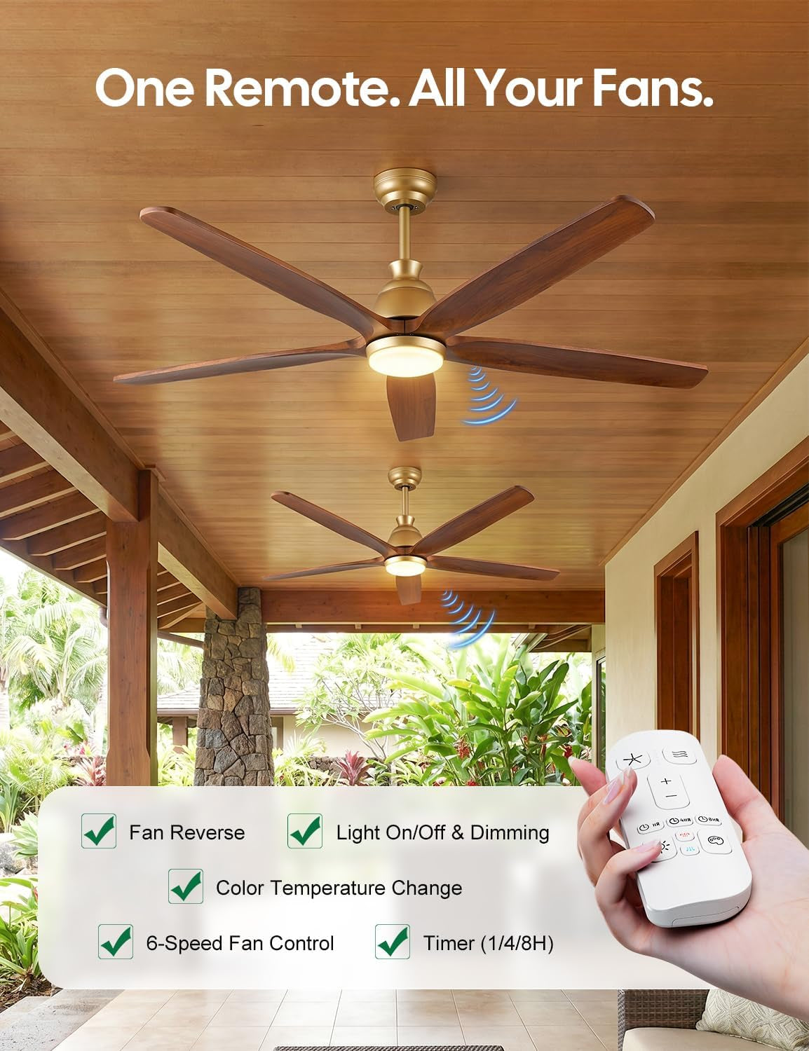 Two gold-brass ceiling fans with walnut blades mounted on a wooden porch ceiling with a remote control held in the foreground
