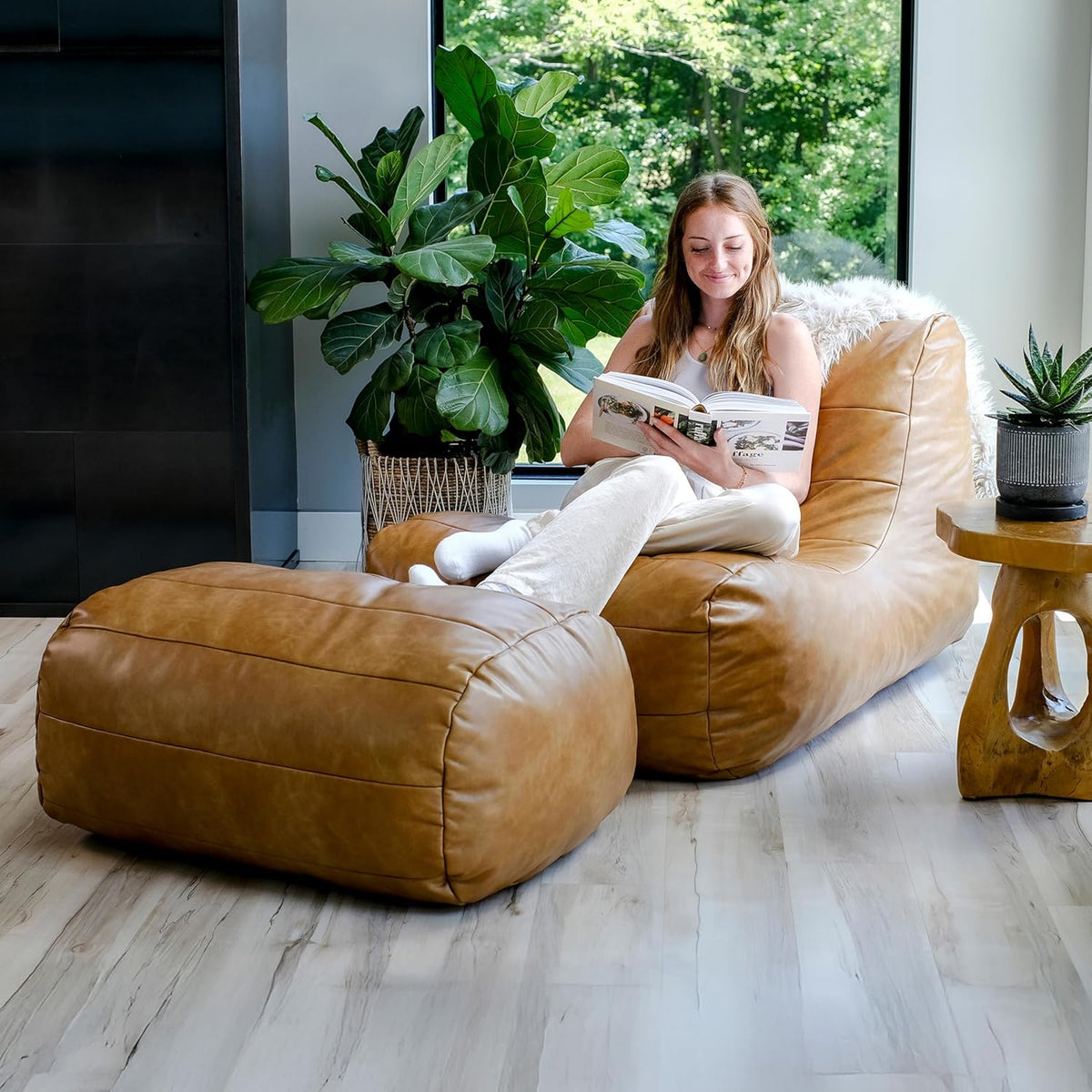 Caramel tan lounge chair and ottoman in a bright living room, side view with person reading