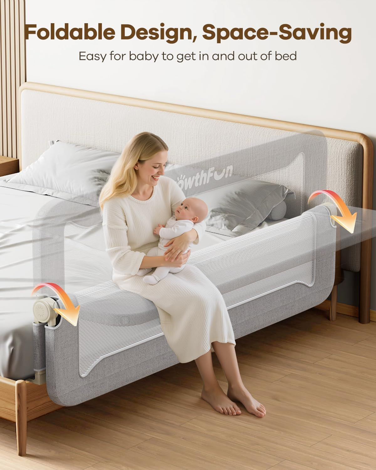 Woman sitting on bed holding a baby next to a foldable mesh bed rail shown folding down.