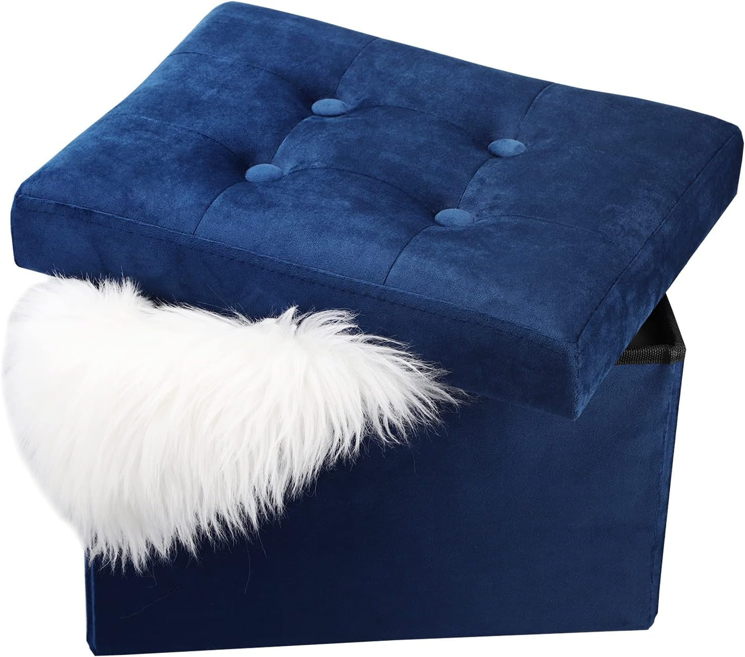 Angled close-up of a navy blue tufted storage ottoman with lid partially open and a white faux fur accent draped over the