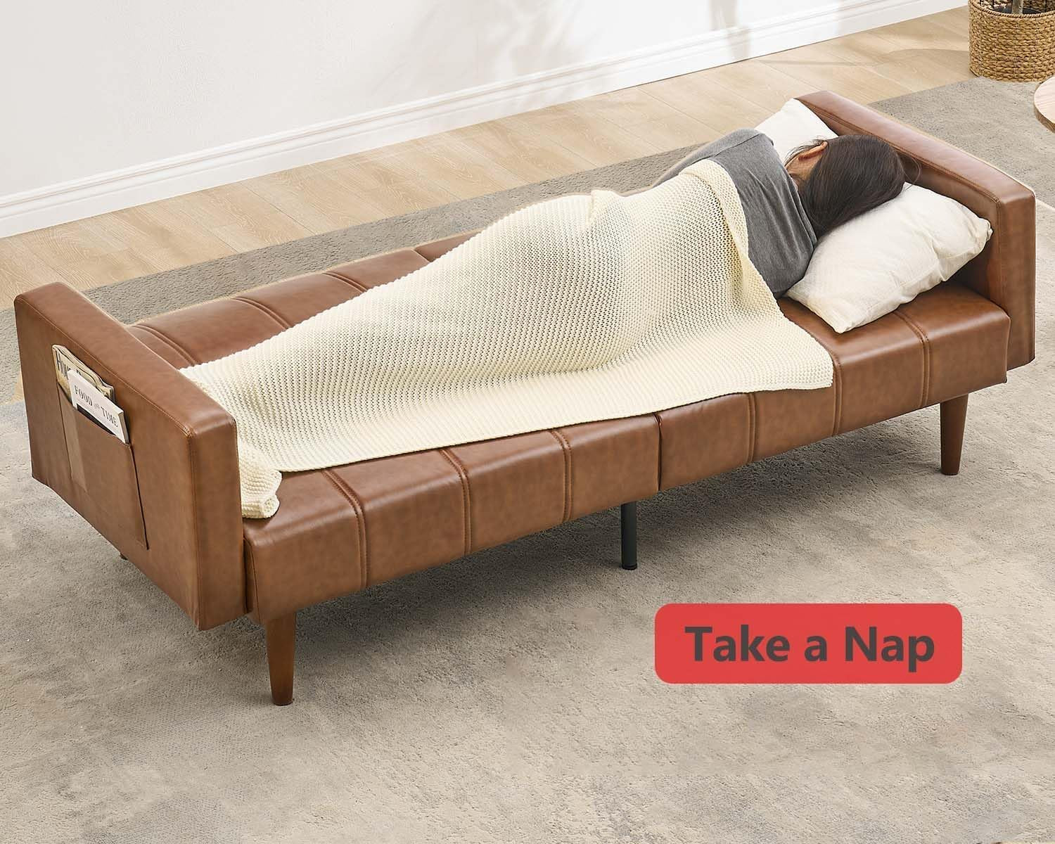 Futon sofa converted to flat sleeper with a person napping and a blanket