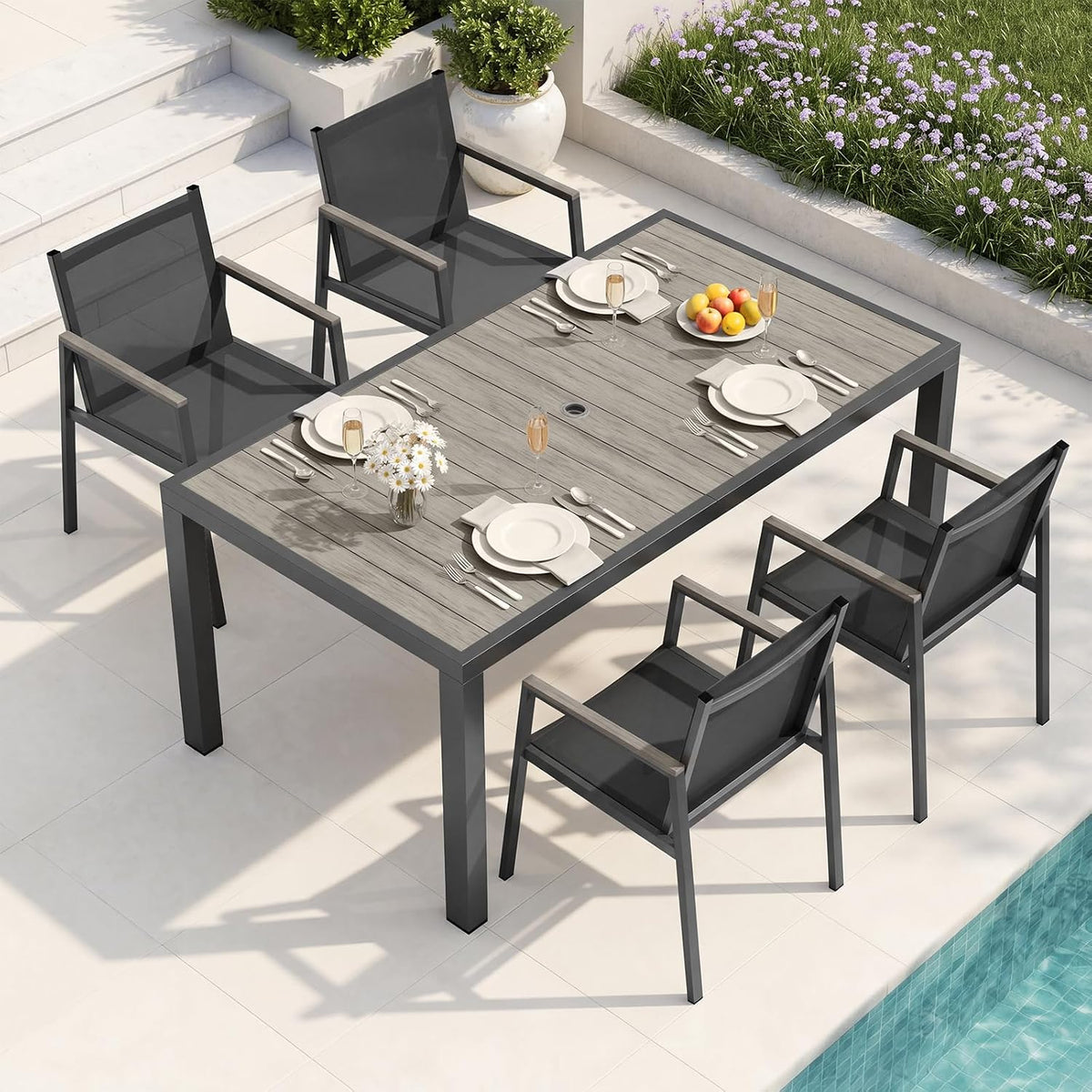 Overhead shot of a gray-weathered wood tabletop on a dark frame with matching dark chairs beside a pool.