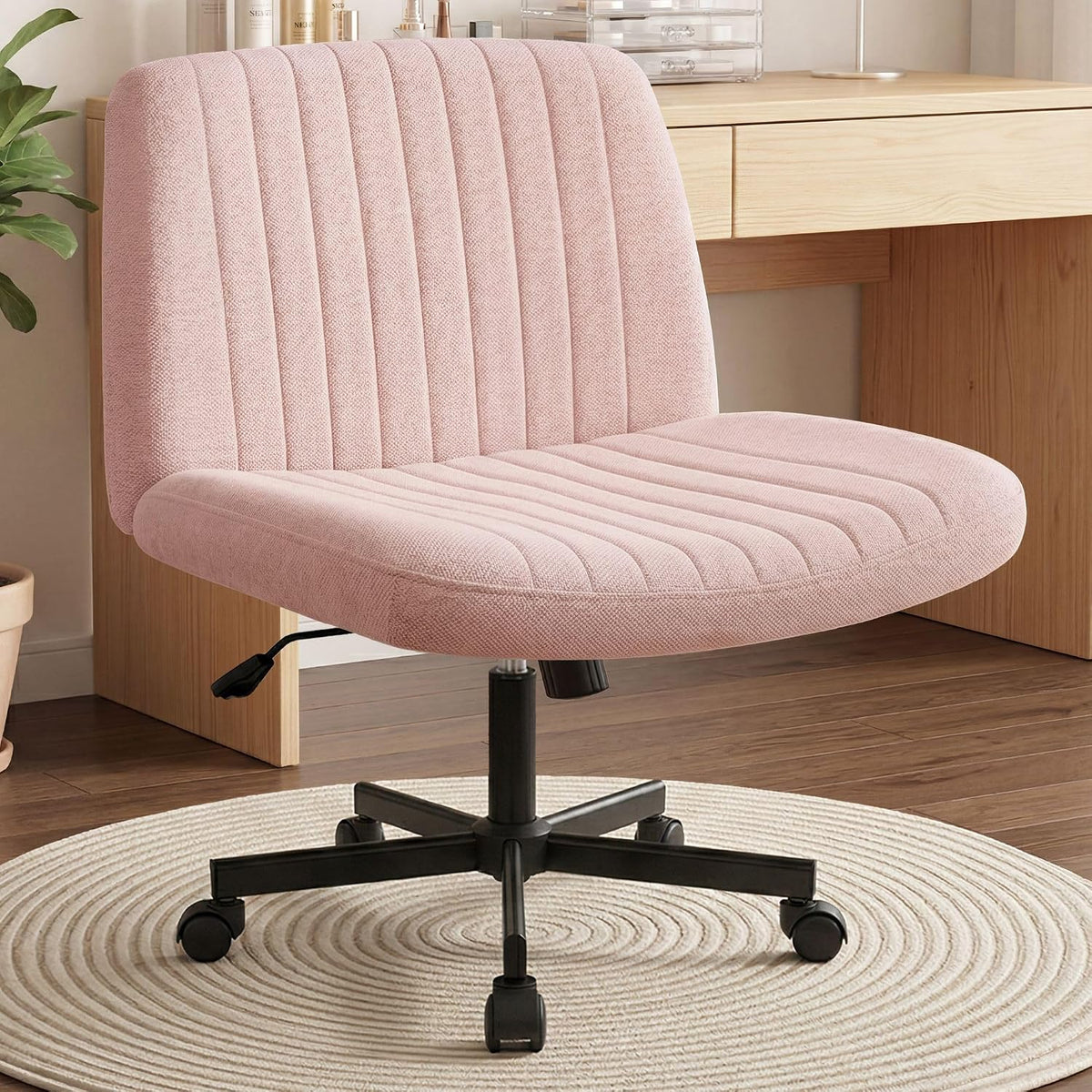 Front three-quarter view of a light pink upholstered swivel desk chair on a black five-star base.
