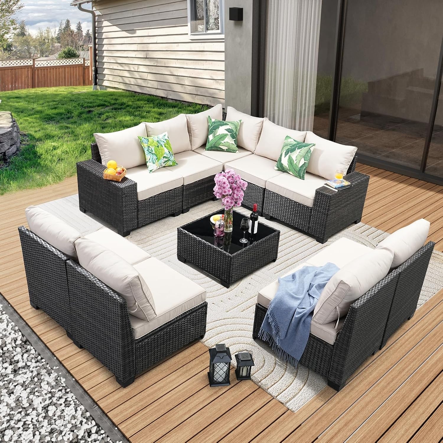 Outdoor patio showing a five-piece dark rattan sectional with beige cushions around a glass-top coffee table.