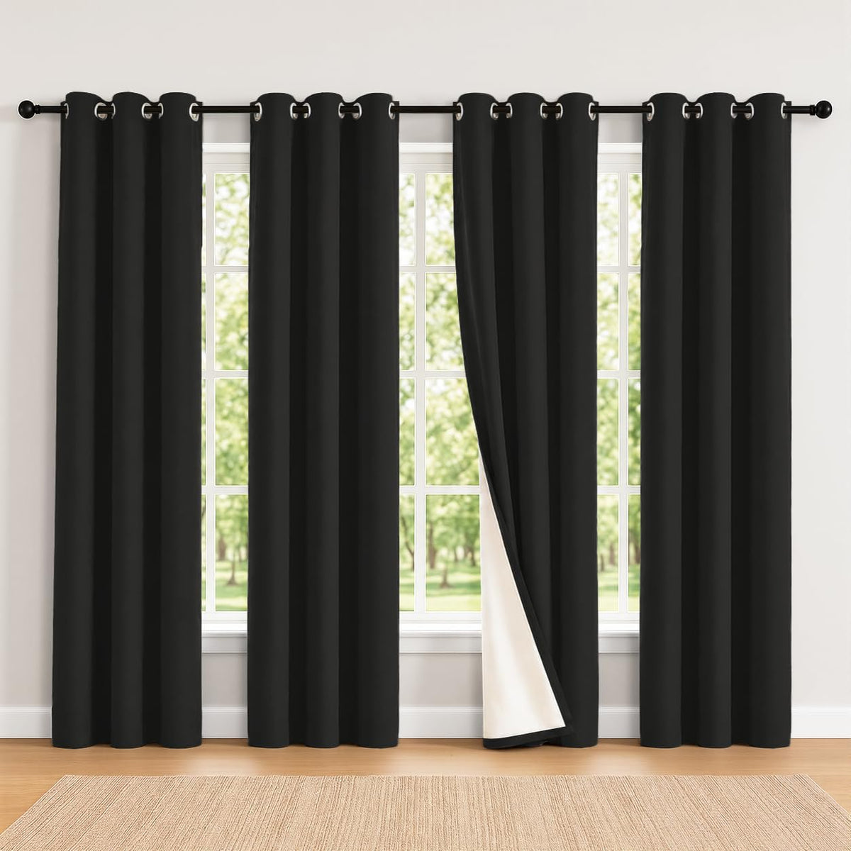 Bright window framed by four black grommet curtains, one panel folded to reveal white inner lining.