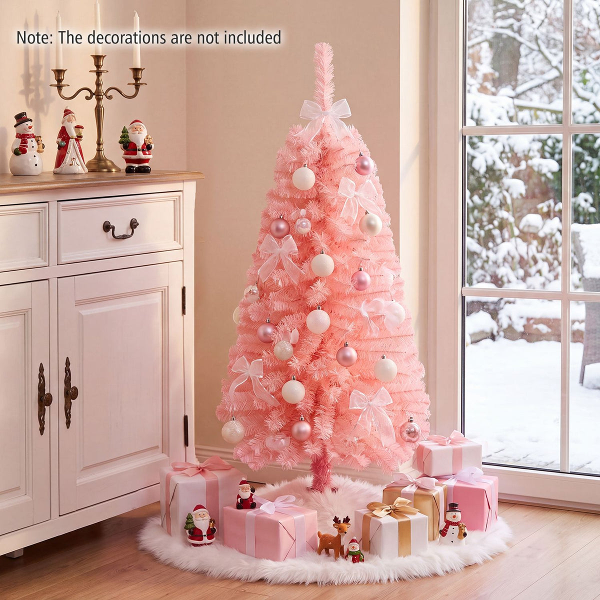 Pink Christmas tree decorated with pale ornaments and bows beside a cabinet and snowy window.