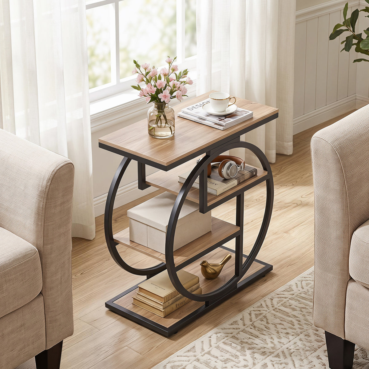Wood-look end table with black circular frame styled beside a sofa with books and flowers.