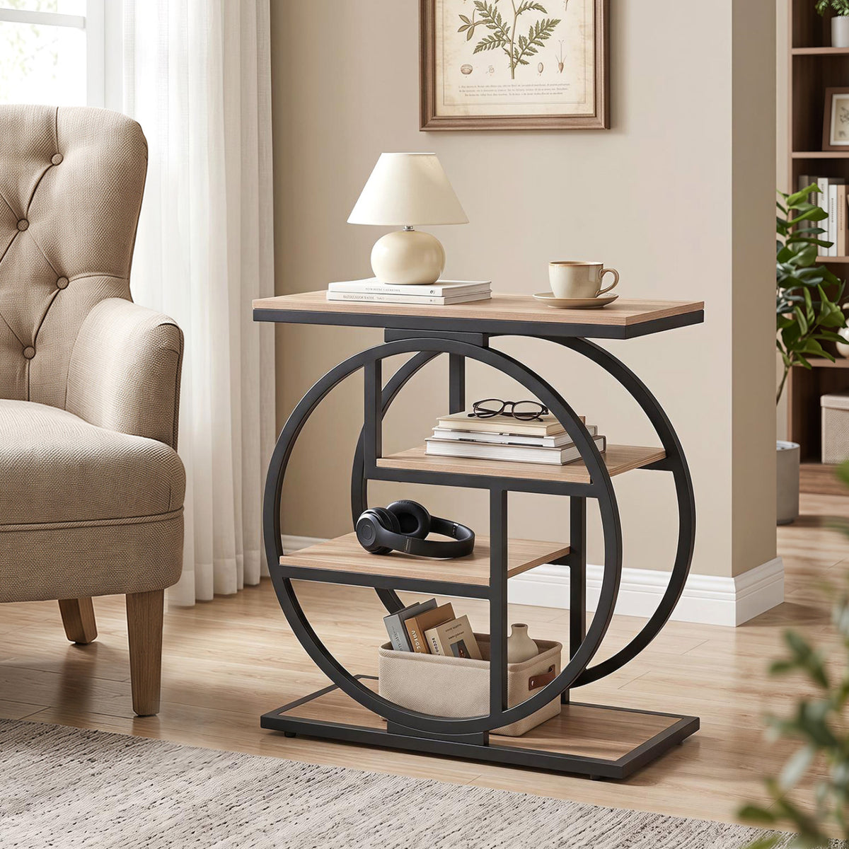 Black circular-frame end table with wood-look shelves beside an armchair, holding a lamp and books.