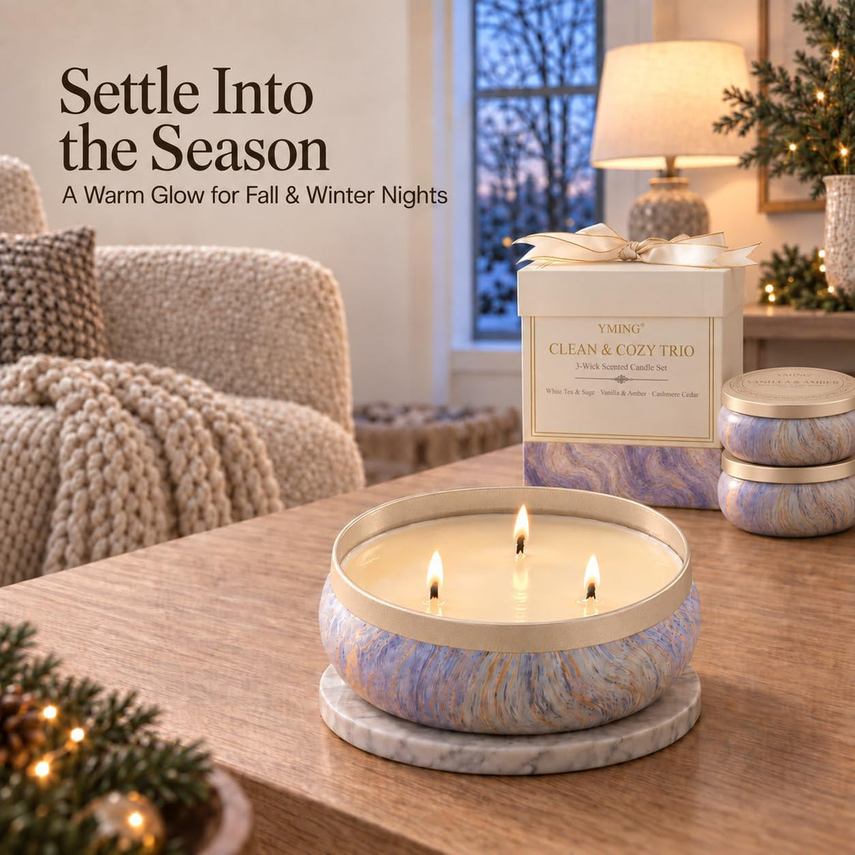 Lit marbled tin candle on a wooden table beside a matching decorative gift box in a cozy living room setting