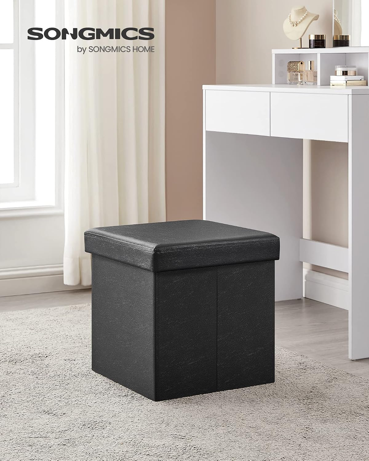 Black storage ottoman placed on a carpeted floor next to a white desk in a room setting