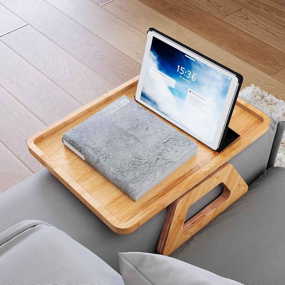 Bamboo tray with a tablet placed in the phone-holder slot and a book on the tray, top-front perspective