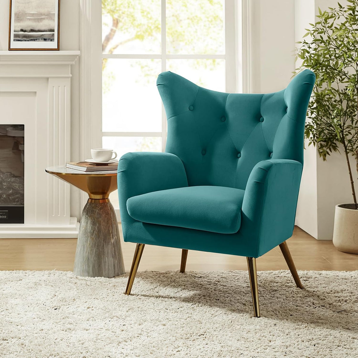 Teal velvet wingback chair angled left beside a gold-topped side table, fireplace and potted plant.