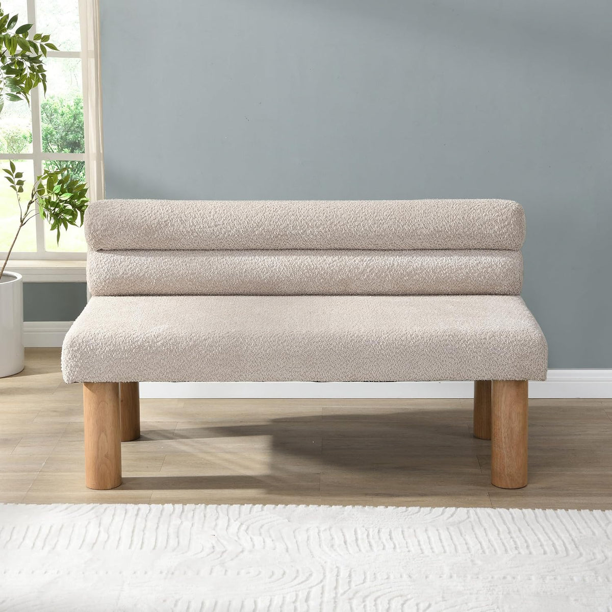 Light beige boucle upholstered long bench with natural round rubberwood legs, front view in a neutral room