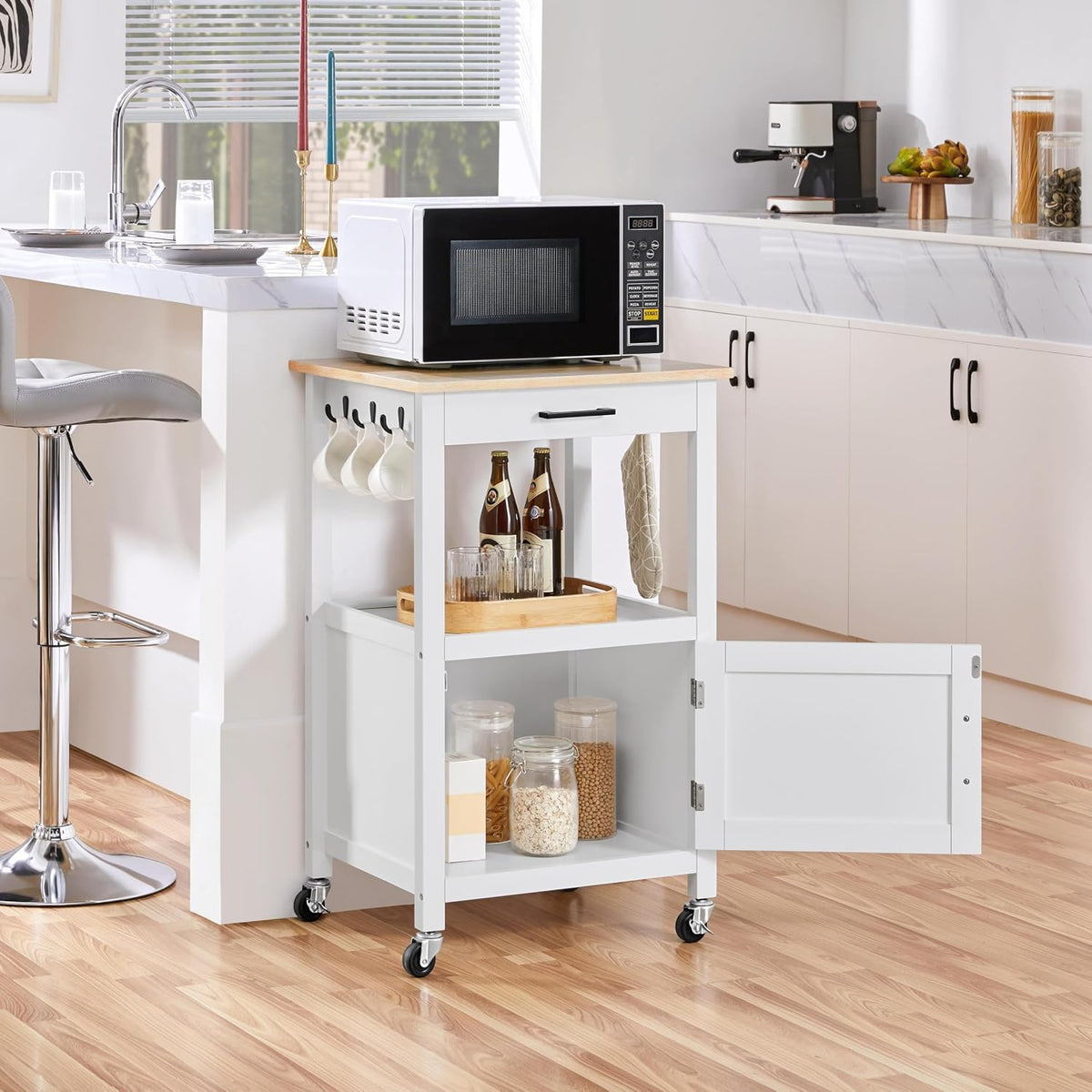 White rolling cart with wood-grain top in a kitchen setting holding a microwave with the lower cabinet open