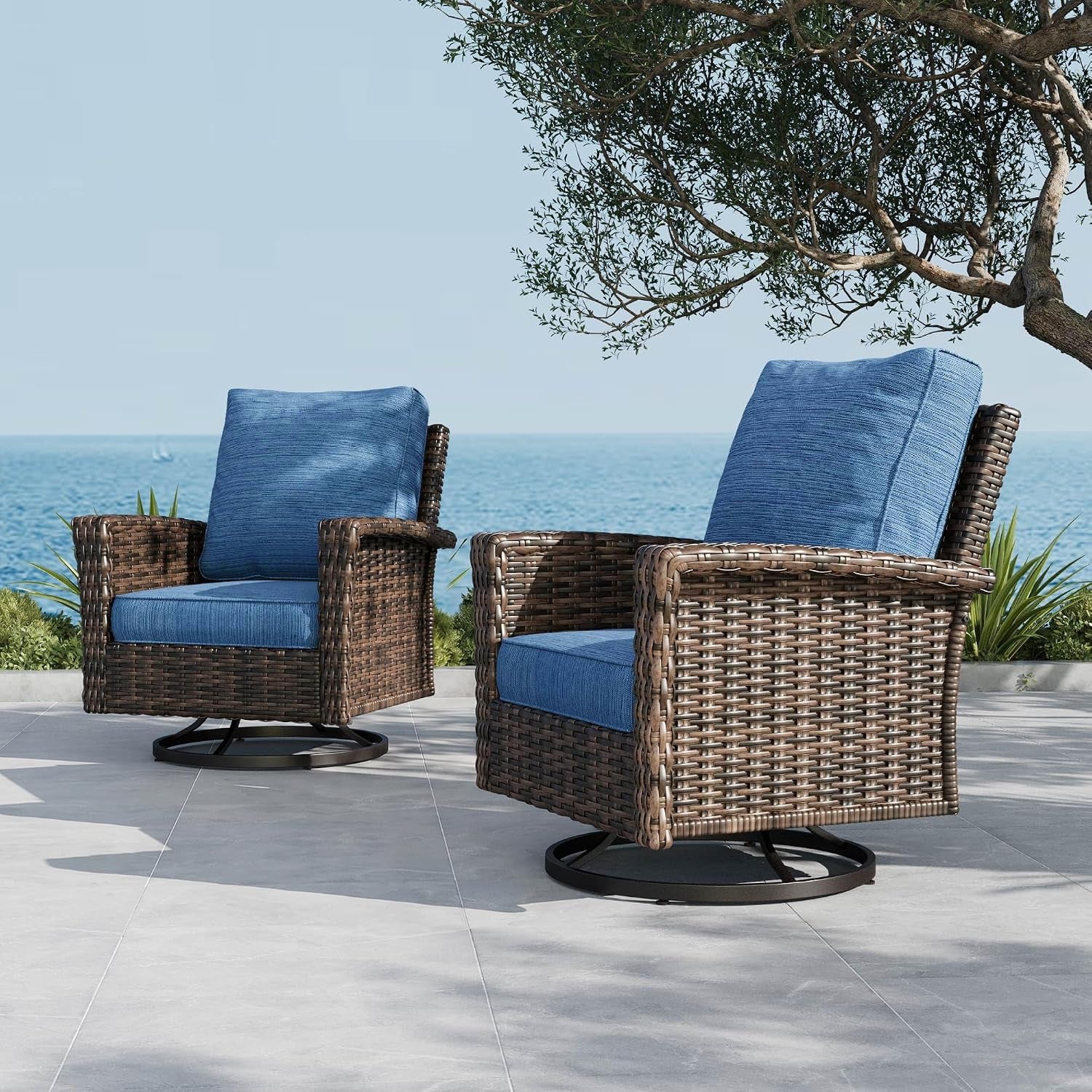 Two brown wicker swivel chairs with blue cushions on a tiled patio by the sea.
