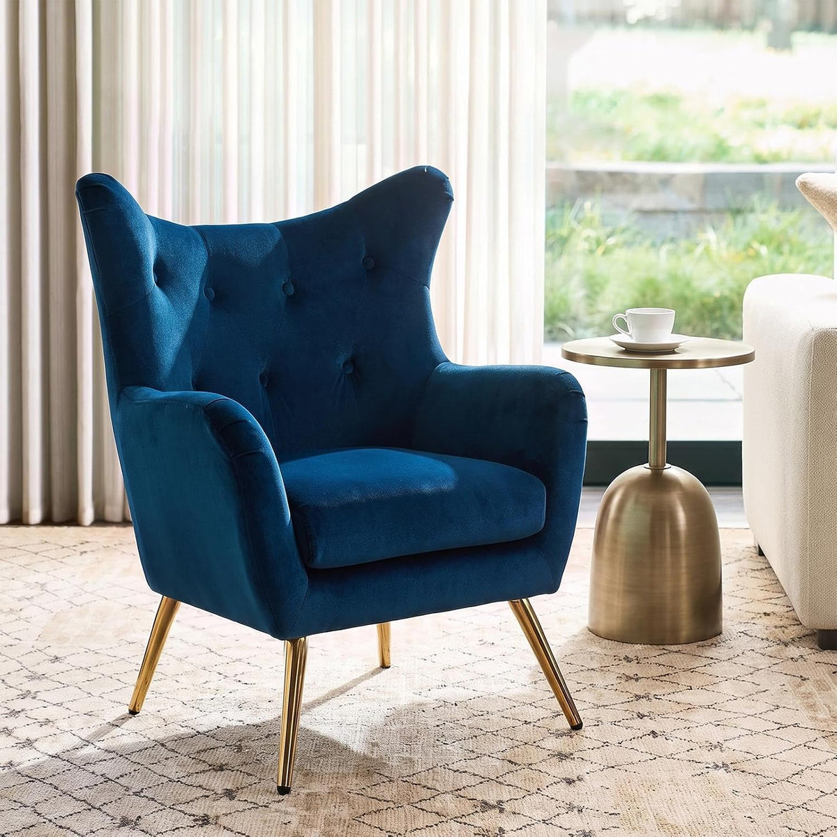 Close side view of a deep navy velvet wingback chair with gold-tone tapered legs