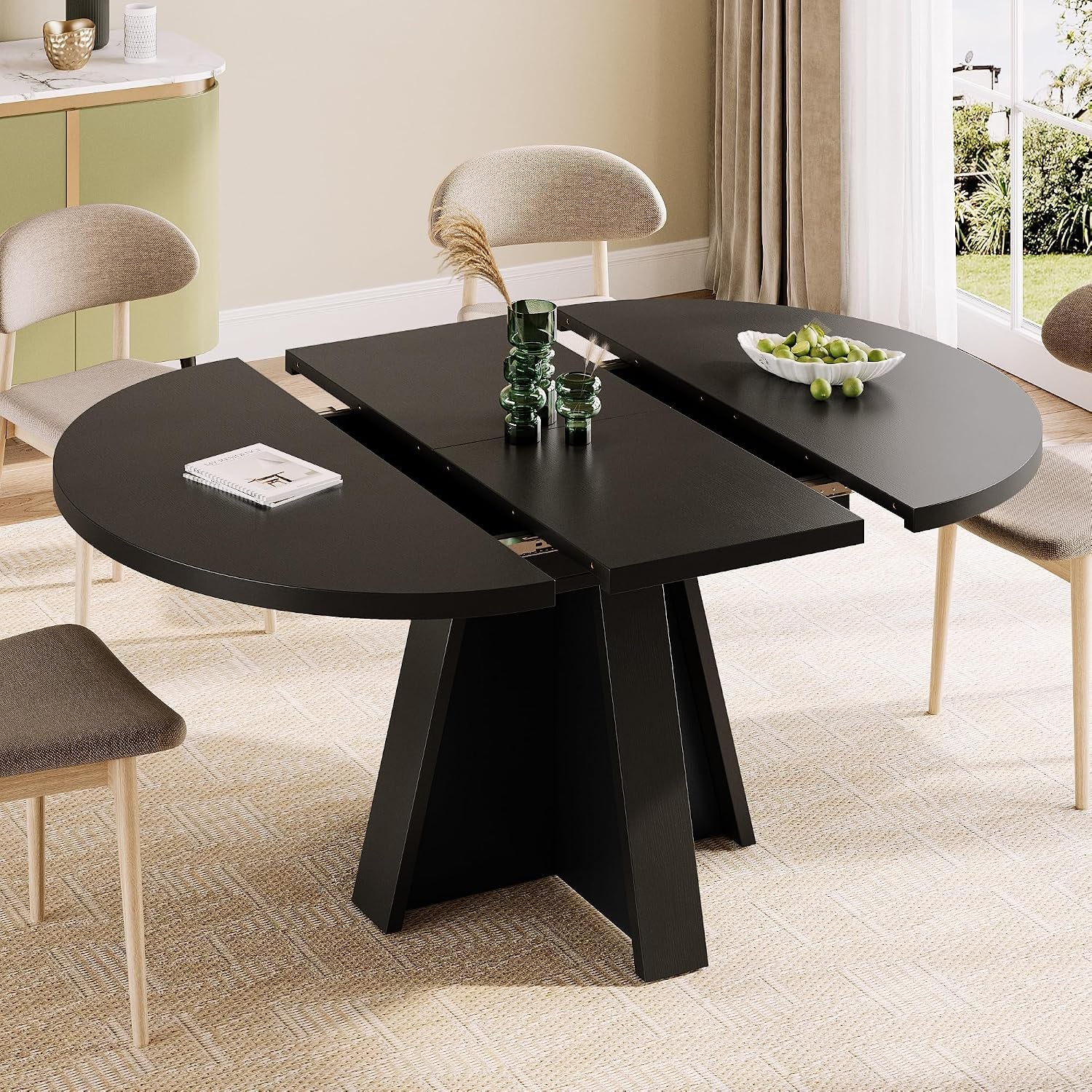 Black extendable round table shown partially extended with three-panel top and pedestal base in a dining setting