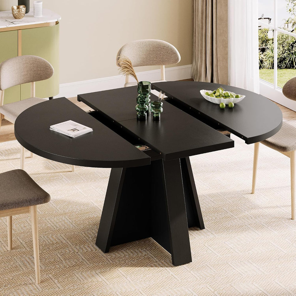 Black extendable round table shown partially extended with three-panel top and pedestal base in a dining setting