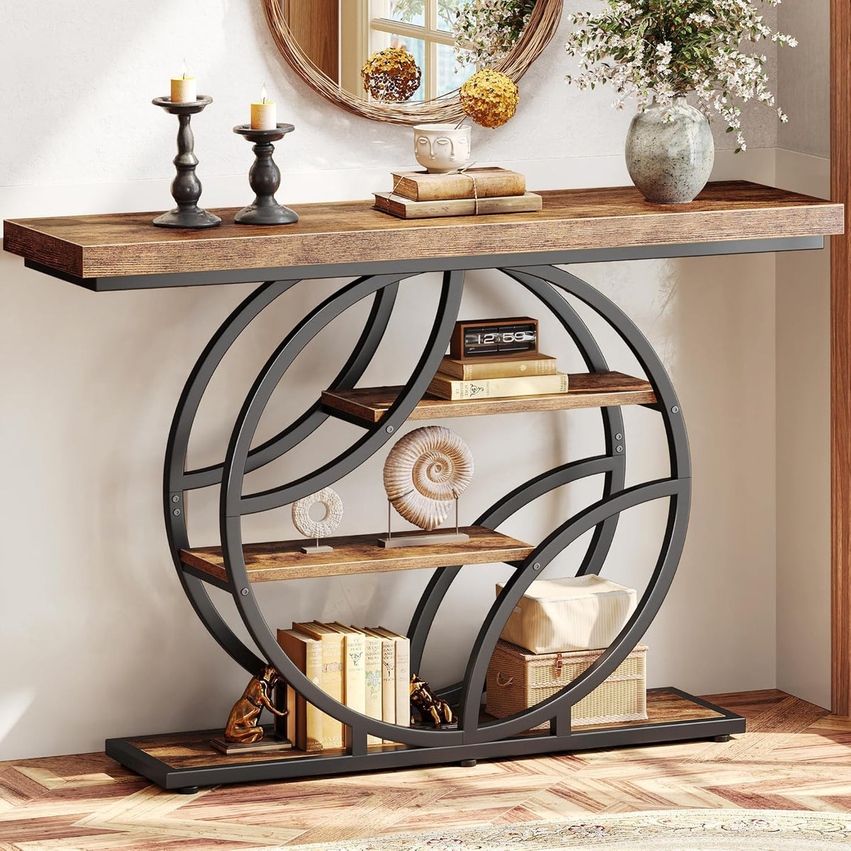 Close frontal view of dark rustic wood top and black O-shaped metal frame with three shelves styled with books and decor.