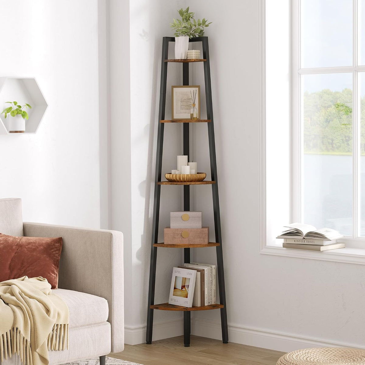 Tall corner ladder shelf with dark frame and wood-toned shelves beside a sofa, styled with candles, framed art and stacked