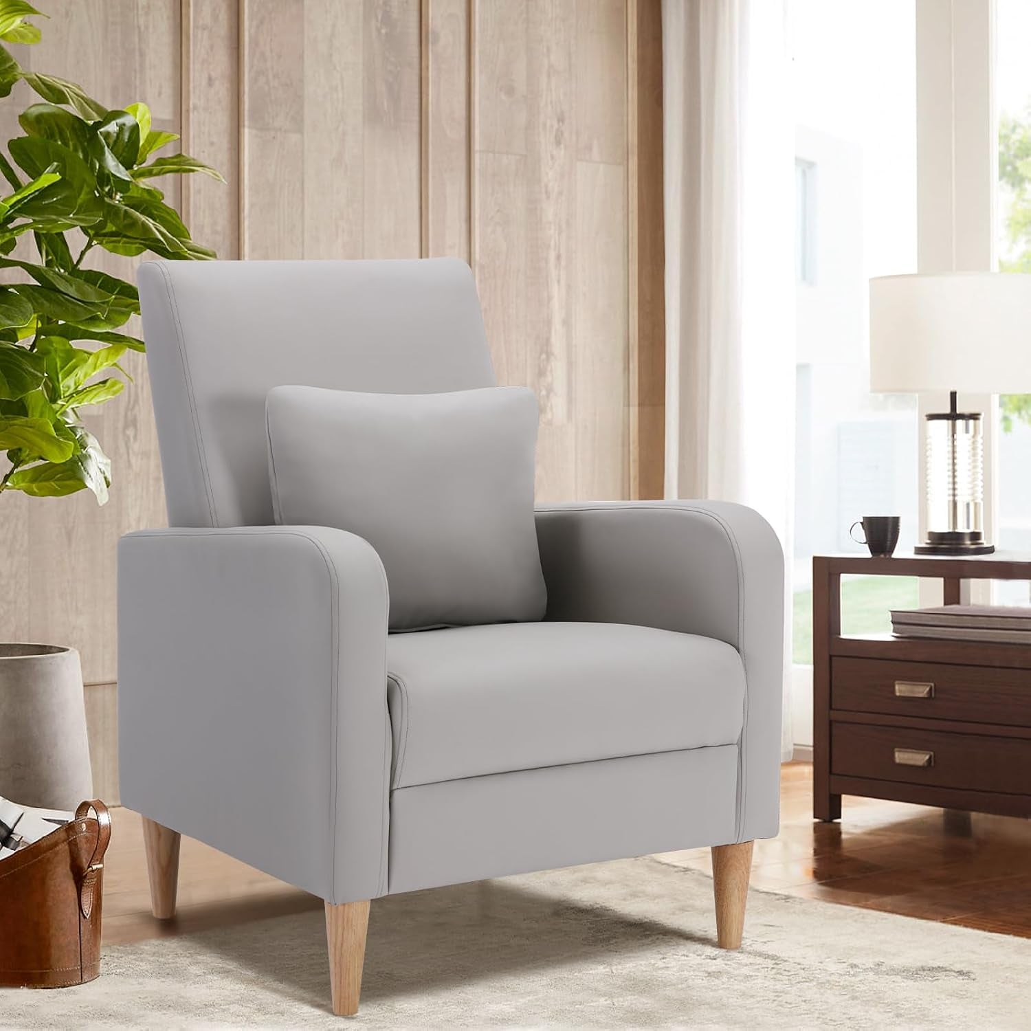 Single high-back chair with removable pillow in a bright room next to a wooden side table and plant