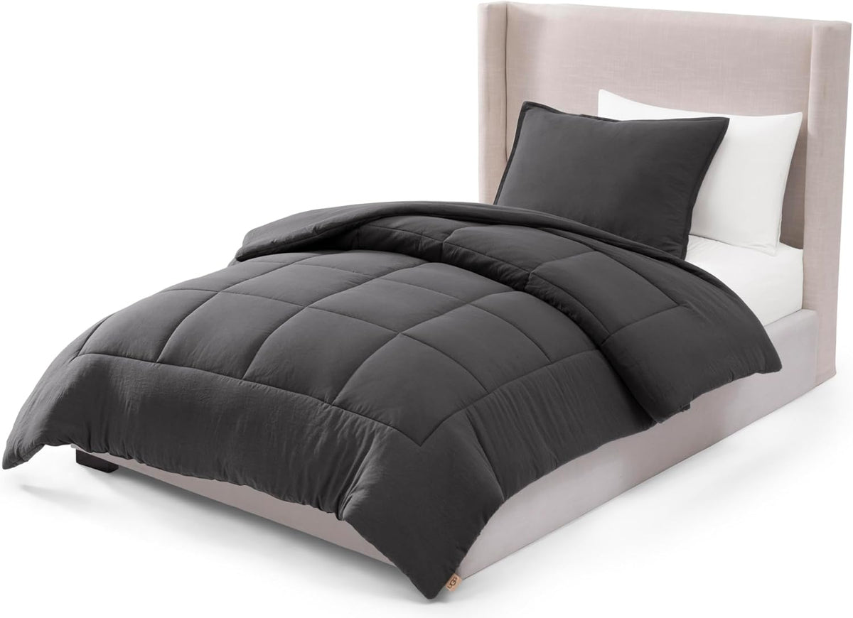 Charcoal box-stitched comforter folded back over a made bed with a dark matching sham