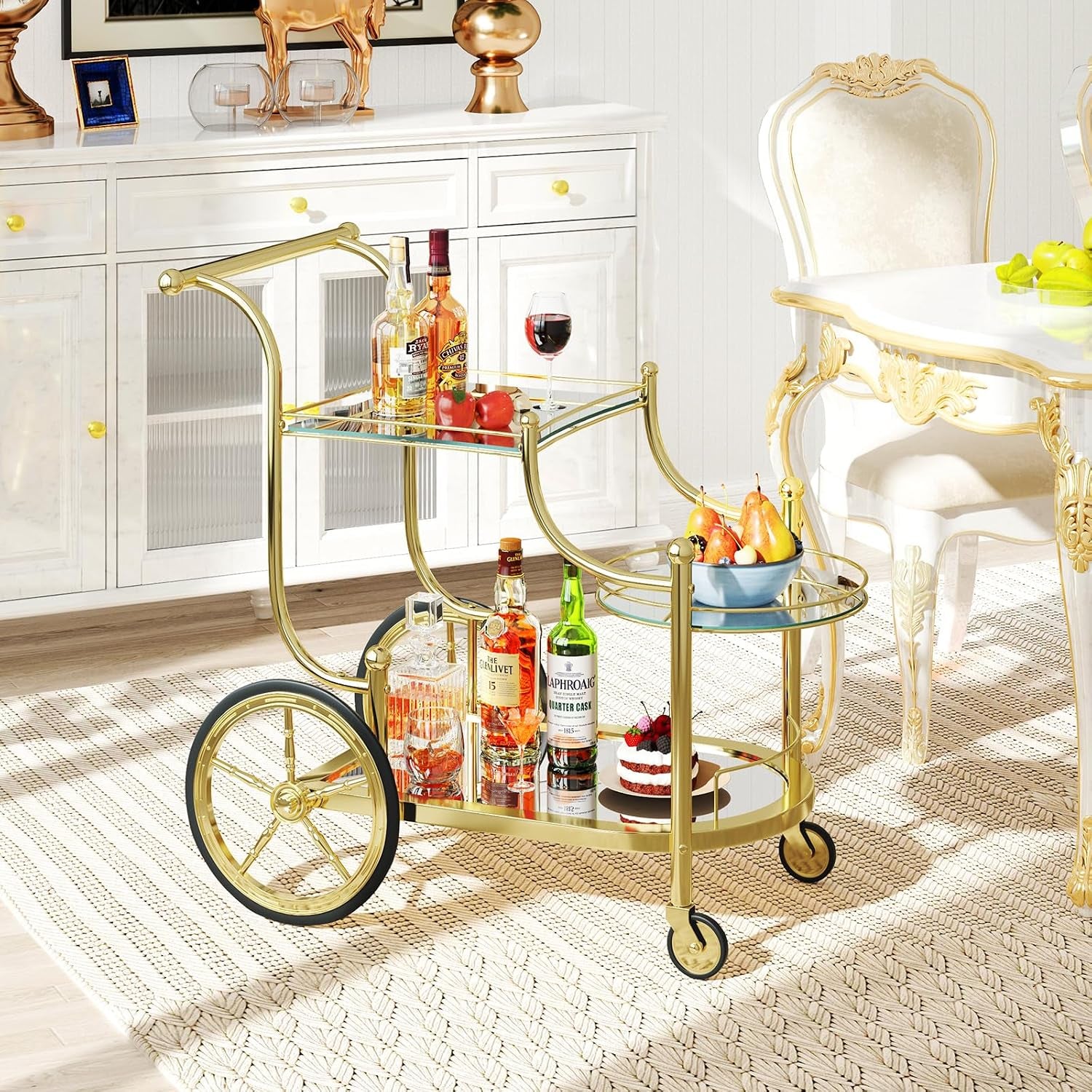 Gold 3-tier bar cart styled in a dining room with bottles and a wine glass on the mirrored top and bottom shelves