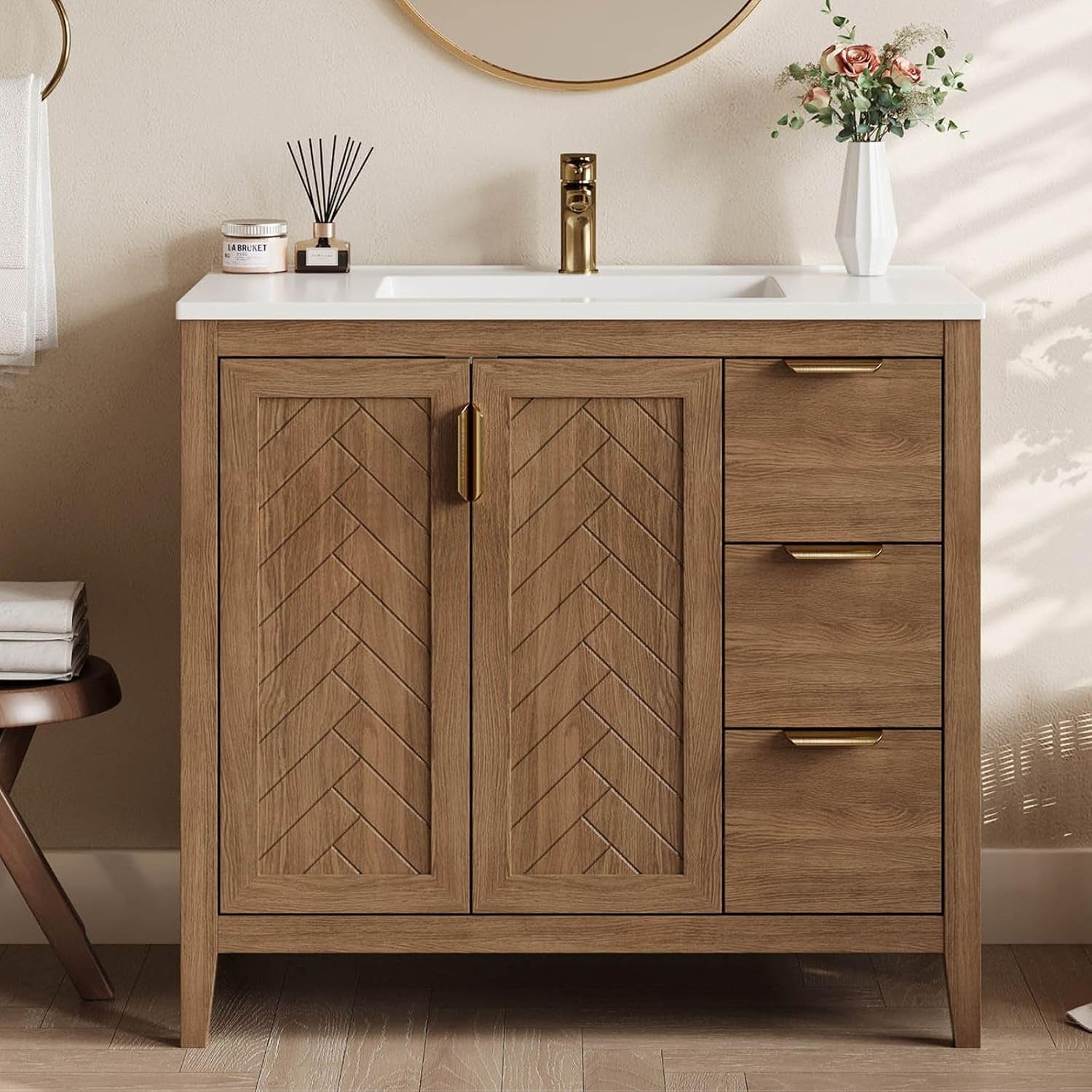 Front view of brown bathroom vanity with chevron inset doors, white integral sink and gold handles