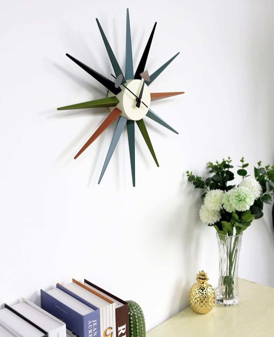 Multicolor sunburst wall clock on a white wall beside books and a glass vase with white flowers