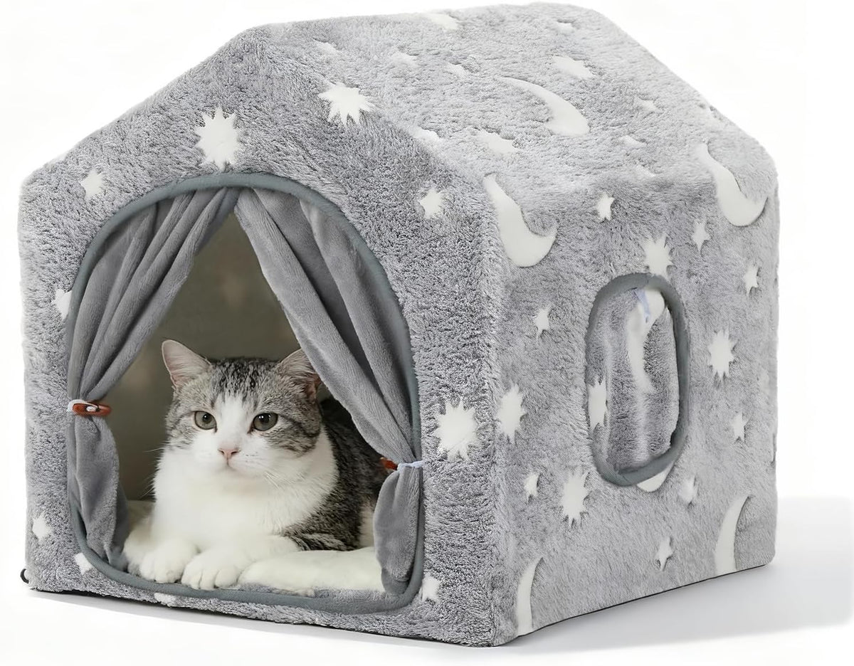 Close-up studio view of the grey moon-and-star plush house with a cat reclining inside and a round side port visible.