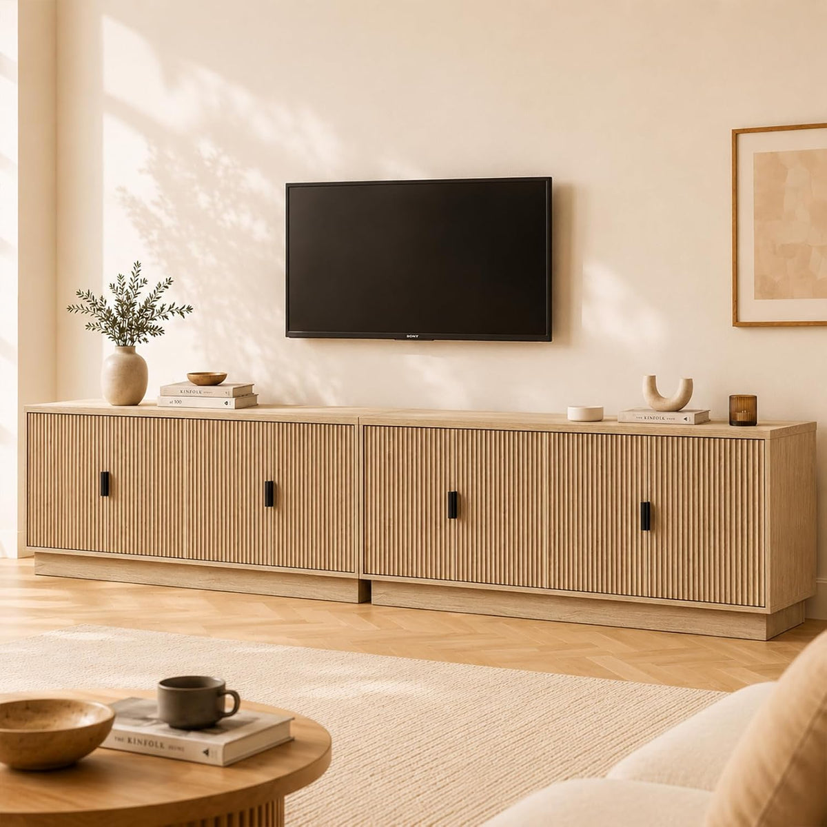 Long light-oak media cabinet with fluted fronts and black rectangular pulls beneath a wall-mounted TV.