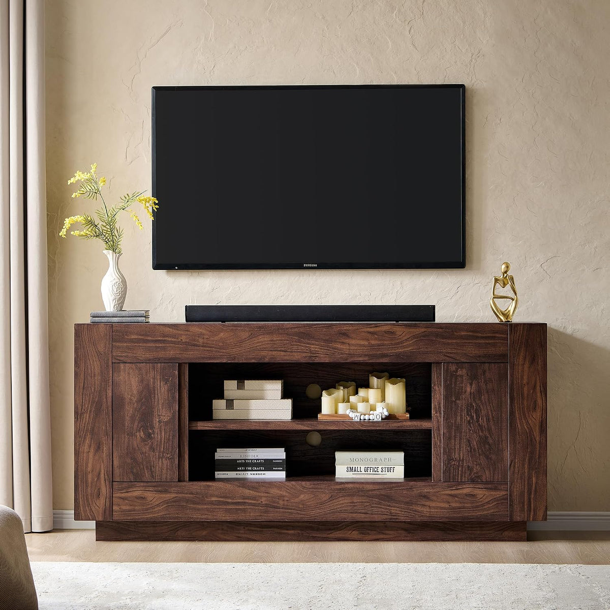 Dark brown wood TV console under a mounted TV, open shelving displaying books and candles