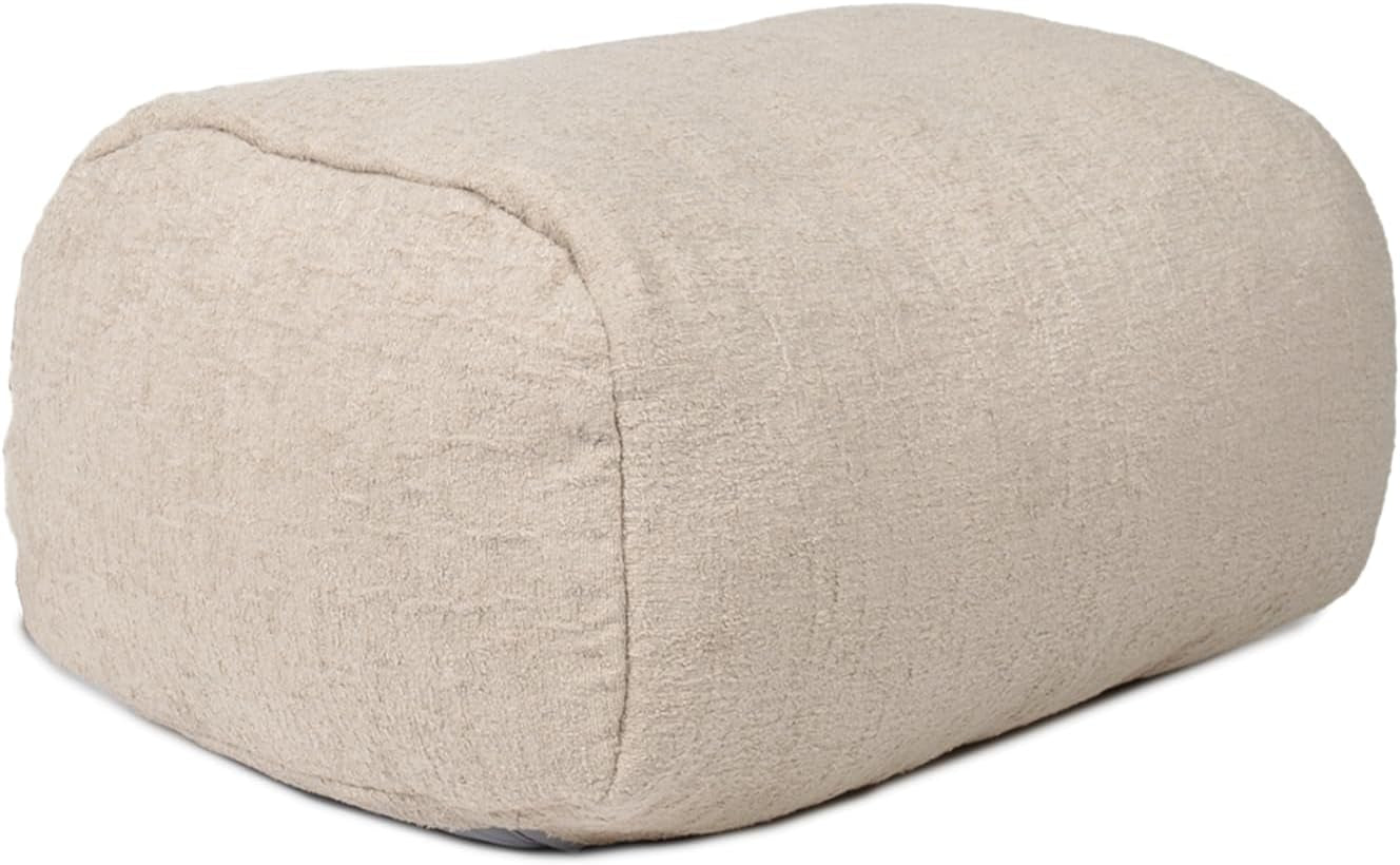 Beige fabric ottoman, angled side view showing rounded rectangular shape